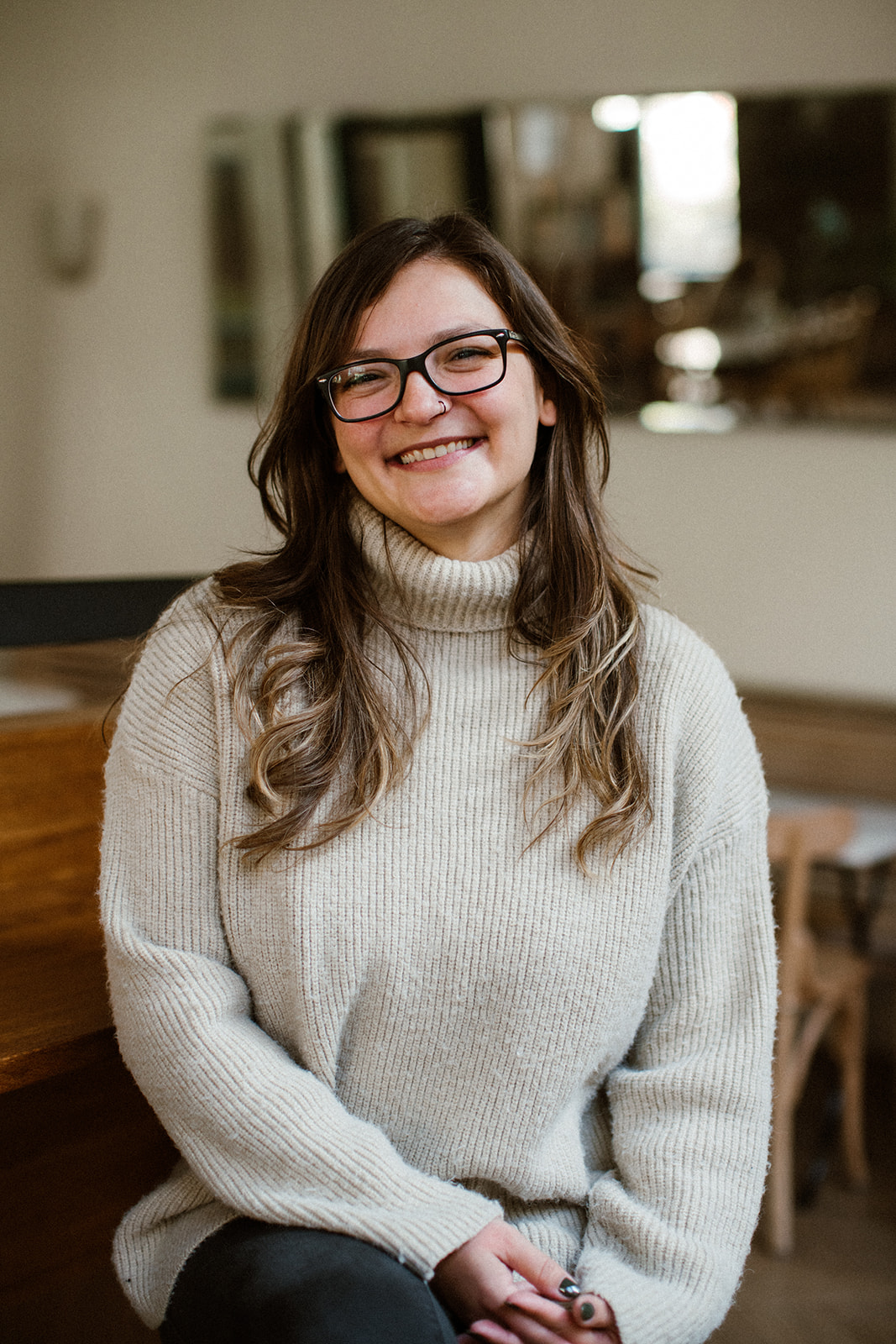 Camila, smiling, in a cream turtleneck